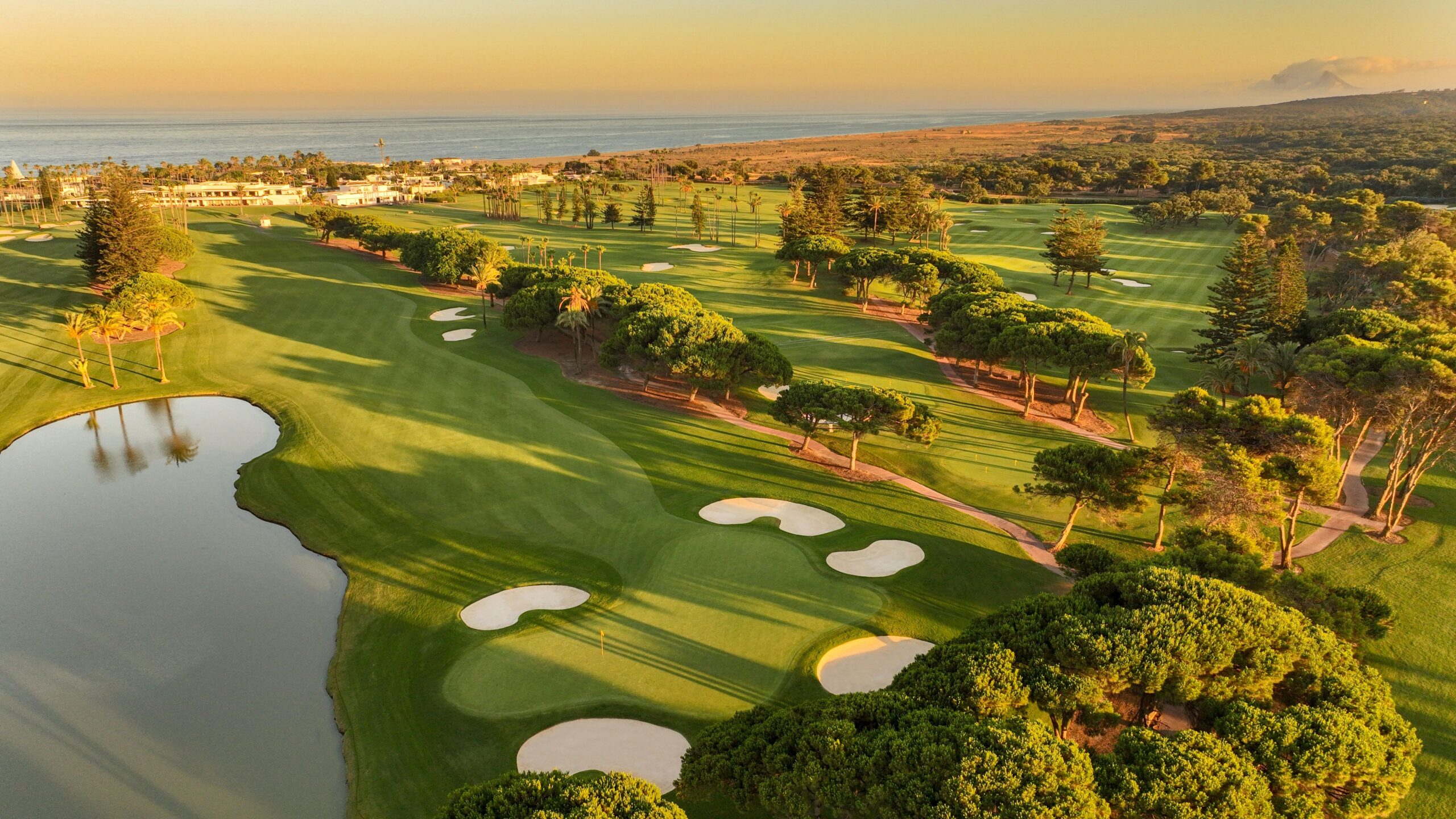 Aerial view of a golf course in Sotogrande with coastal scenery and Gibraltar in the background.